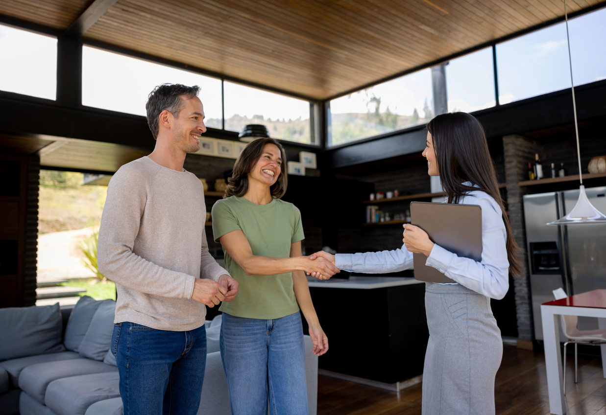 Couple shaking the rental agent's hand in a house
